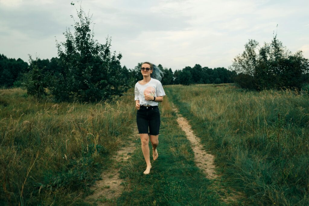 Barefoot woman walking on a grassy path in a rural area on a summer day.