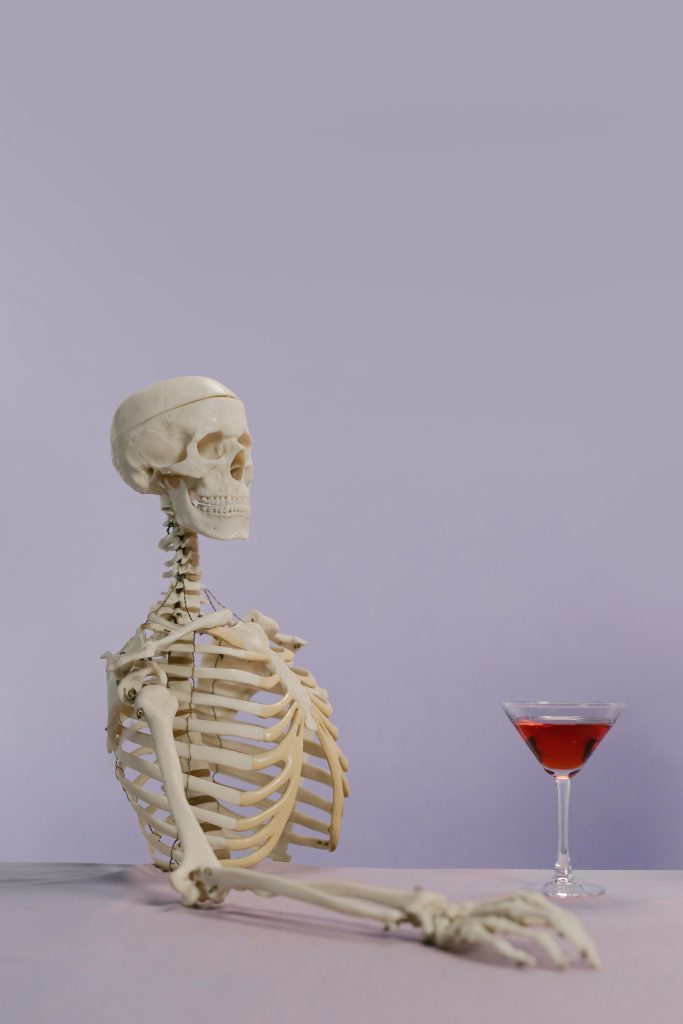 Skeleton model with a cocktail glass on a purple background, playful and intriguing vibe.