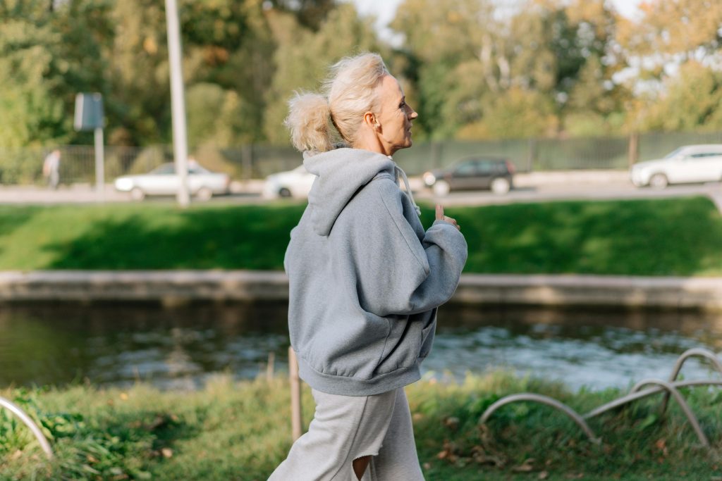 Elderly woman jogging in a park, enjoying a healthy lifestyle outdoors.