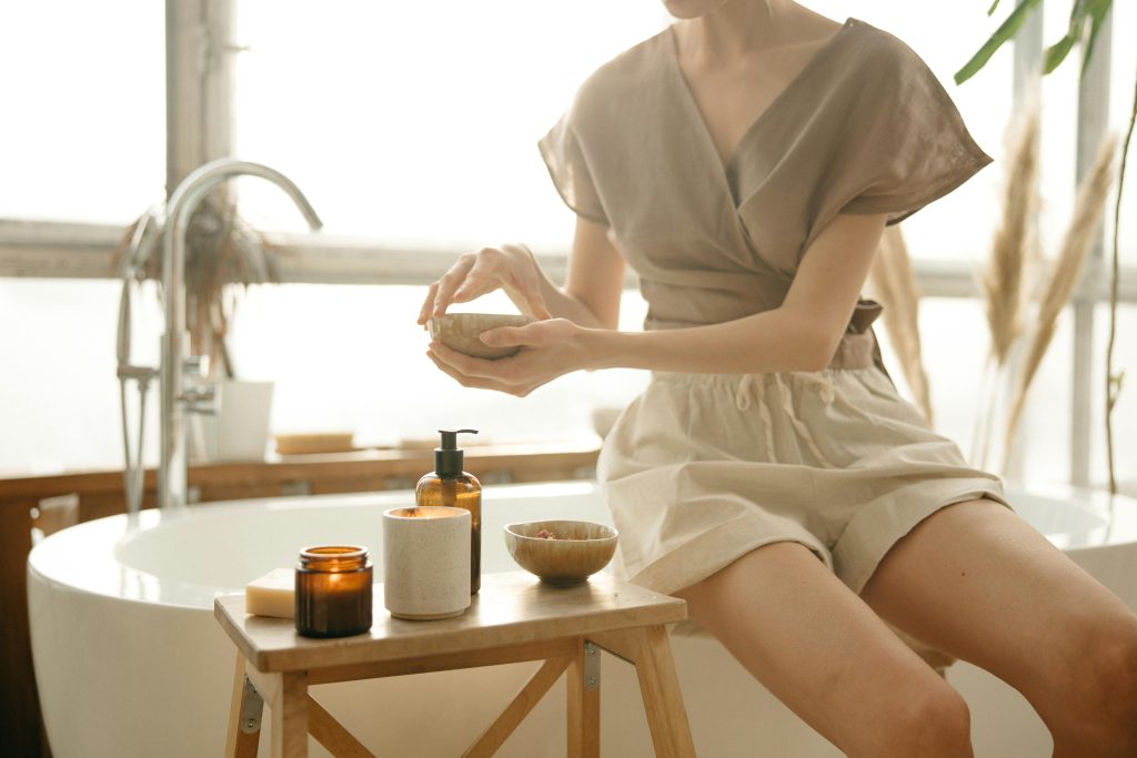 Relaxing self-care scene with woman using body care products in a stylish bathroom setting.