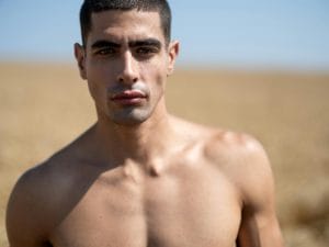 Strong male portrait in outdoor sunlight, exuding confidence and strength.