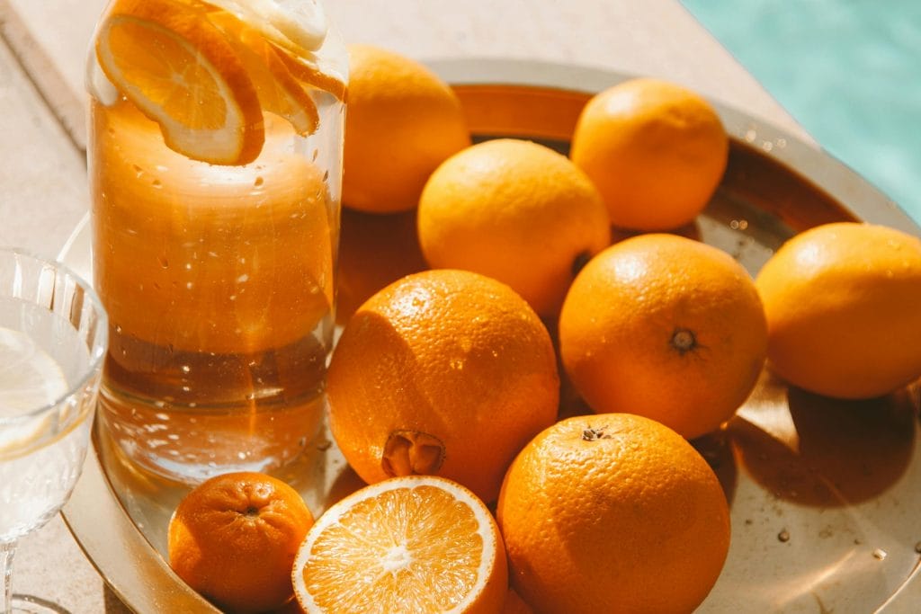 Bright and fresh citrus fruits with a glass pitcher of orange juice on a sunny tray setting.